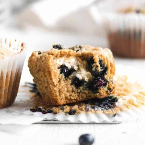 close up of unwrapped blueberry cream cheese muffin unwrapped with a bite removed