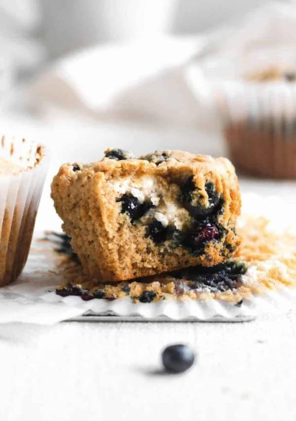 close up of unwrapped blueberry cream cheese muffin unwrapped with a bite removed