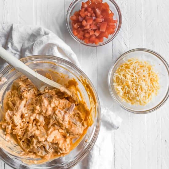 a bowl full of ingredients for a Mexican dip featuring Buffalo chicken nachos.