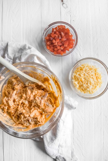 a bowl full of ingredients for a Mexican dip featuring Buffalo chicken nachos.
