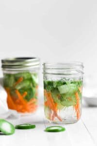 Two mason jars filled with freshly pickled cucumbers and carrots.