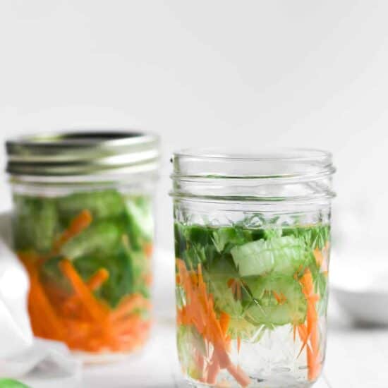 Two mason jars filled with freshly pickled cucumbers and carrots.