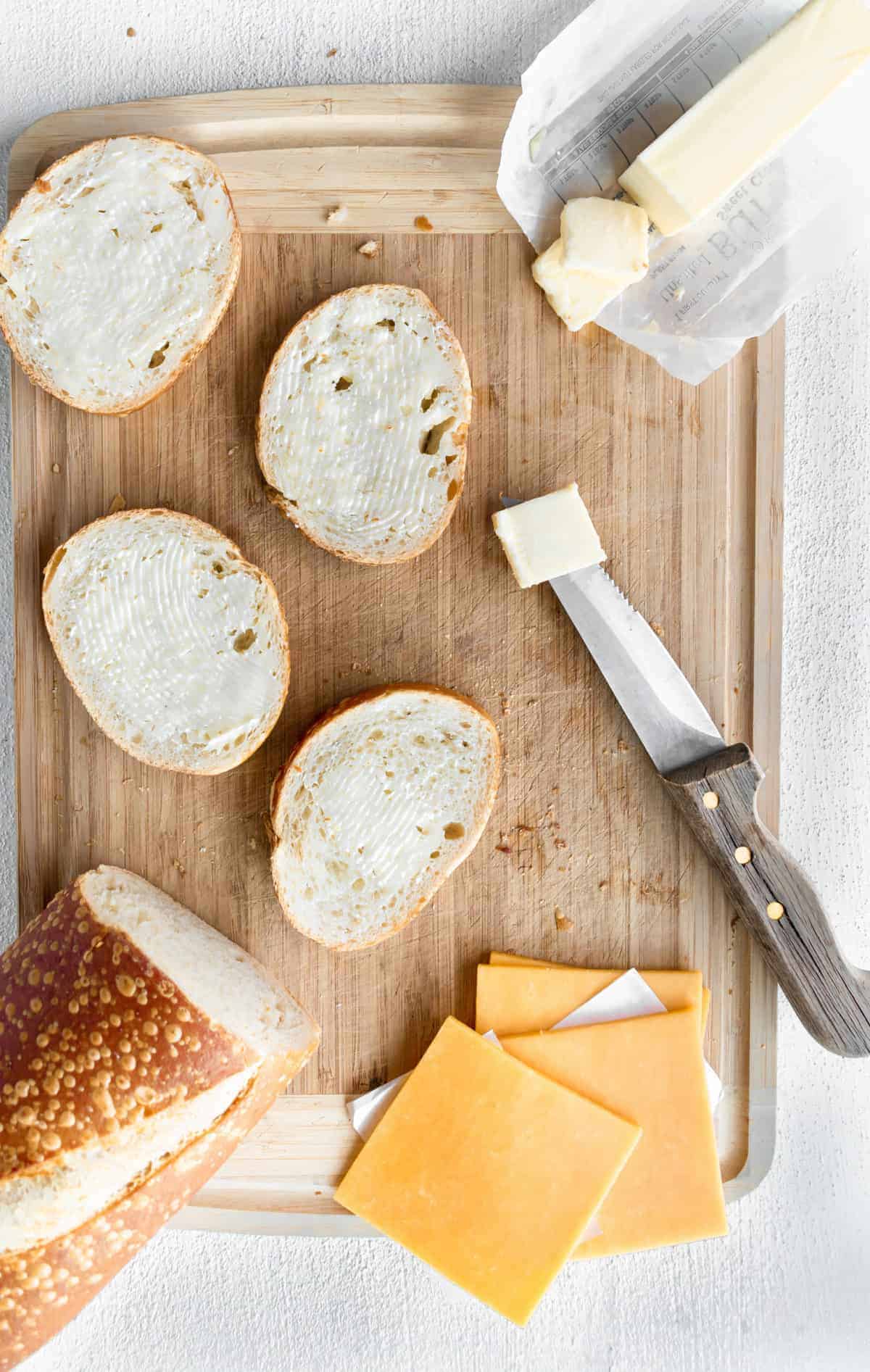 Italian bread, sliced cheese on cutting board.