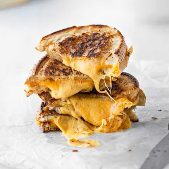 a grilled cheese sandwich is elevated by being stacked on top of a bowl of soup.