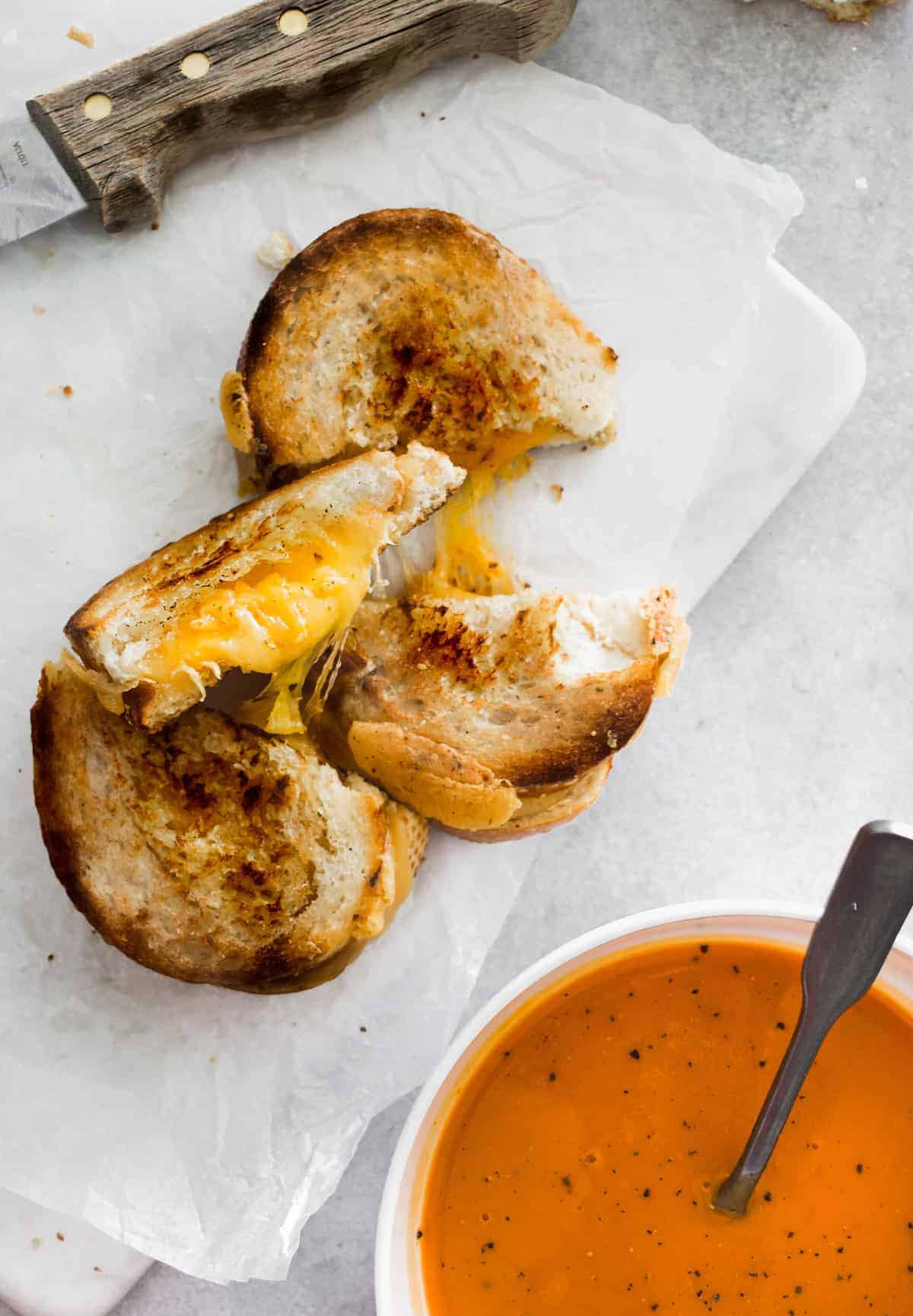 Grilled cheese next to tomato soup.
