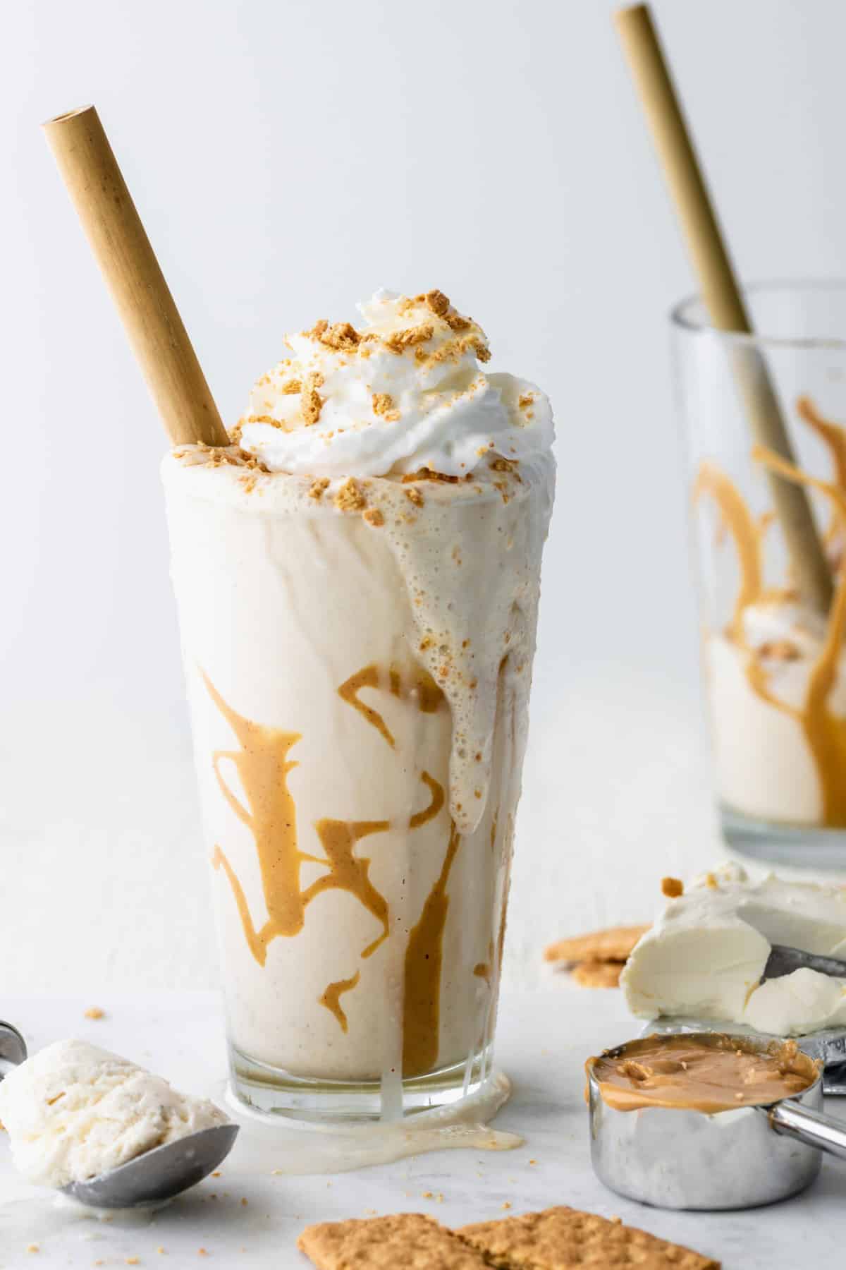 peanut butter cheesecake milkshake in a glass topped with whipped cream.