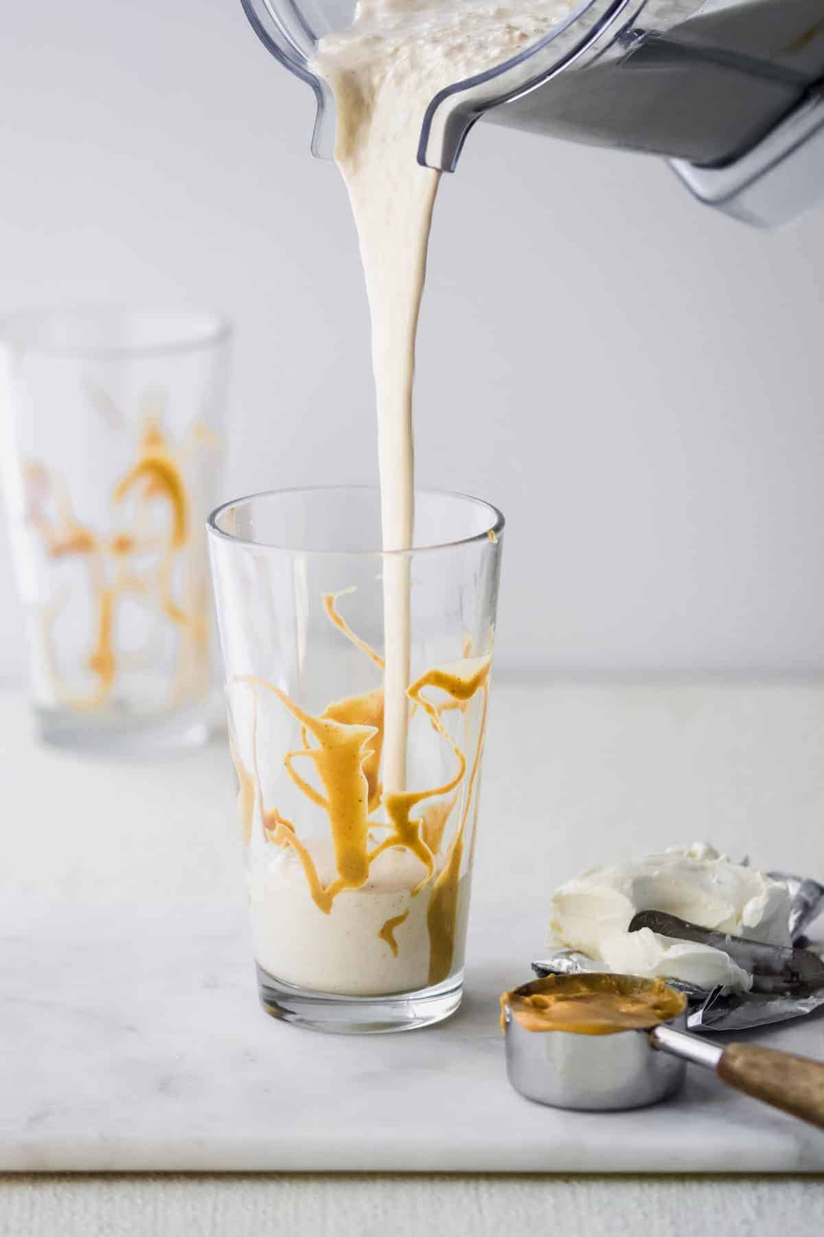 peanut butter cheesecake milkshake being poured from a blender into a glass