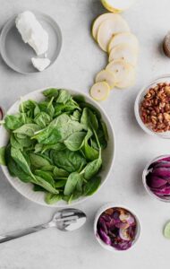 ingredients for a beet and goat cheese salad with spinach and red onion.
