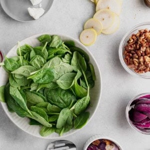 ingredients for a beet and goat cheese salad with spinach and red onion.