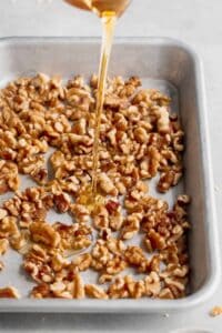 A salad consisting of beets and goat cheese topped with honey-drizzled walnuts on a baking sheet.
