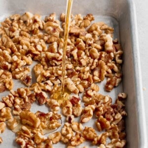 A salad consisting of beets and goat cheese topped with honey-drizzled walnuts on a baking sheet.