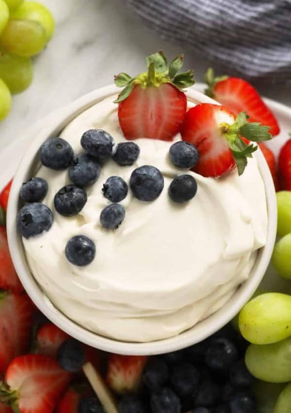 close up image of cream cheese fruit dip in a bowl surrounded by fresh fruit