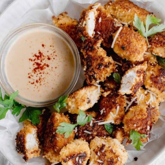 a plate of crispy parmesan chicken nuggets with a dipping sauce