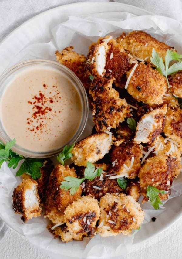a plate of crispy parmesan chicken nuggets with a dipping sauce