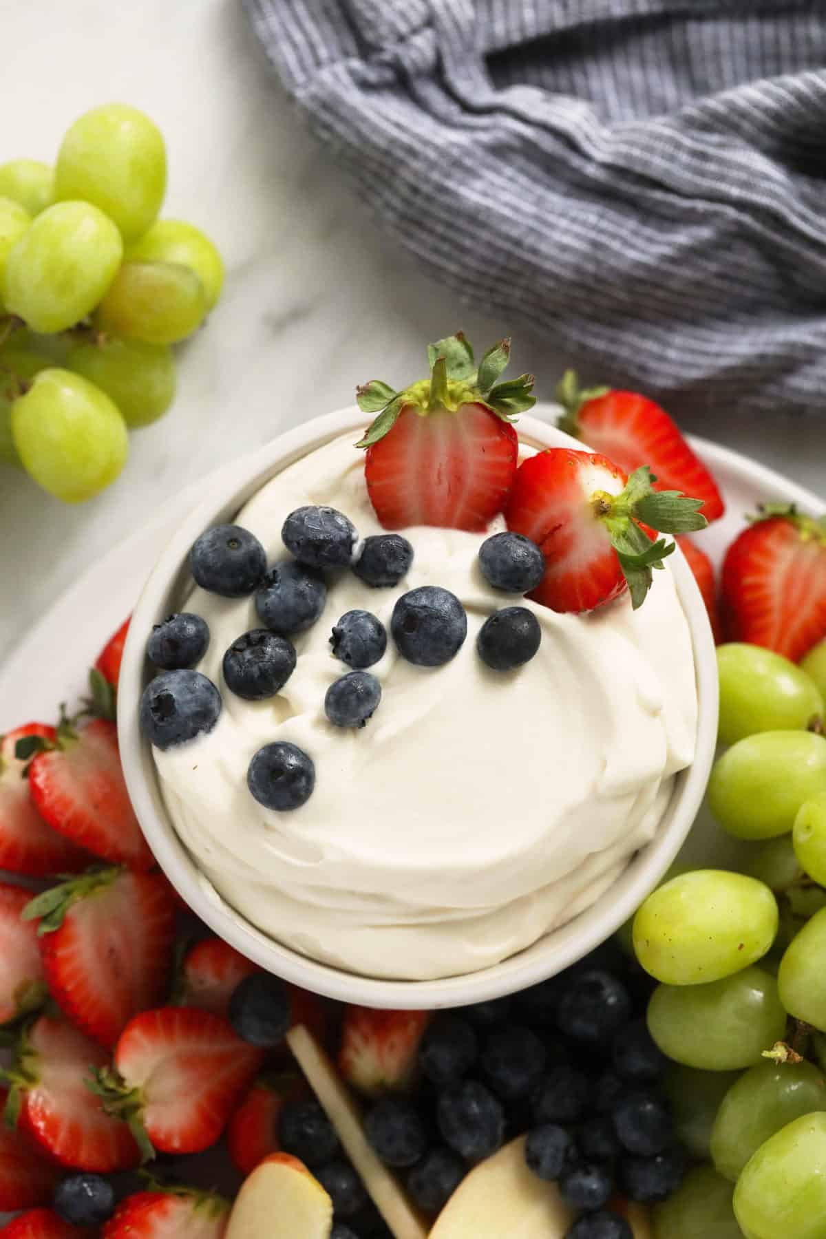 cream cheese fruit dip in a bowl surrounded by fresh fruit.