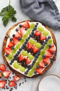 a fruit pizza with strawberries, blueberries and chocolate chips. 
Modified description with keywords: A delectable Fruit Pizza topped with juicy strawberries, fresh blueberries and scrumptious chocolate chips