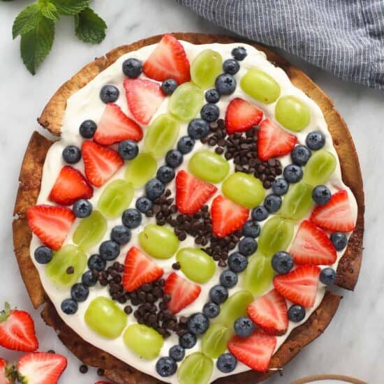 a fruit pizza with strawberries, blueberries and chocolate chips. 
Modified description with keywords: A delectable Fruit Pizza topped with juicy strawberries, fresh blueberries and scrumptious chocolate chips