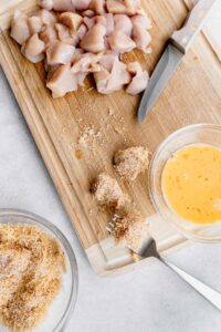 A cutting board with chicken nuggets for chicken fried rice.