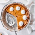 A decadent pumpkin cheesecake pie, with a delicious slice missing.