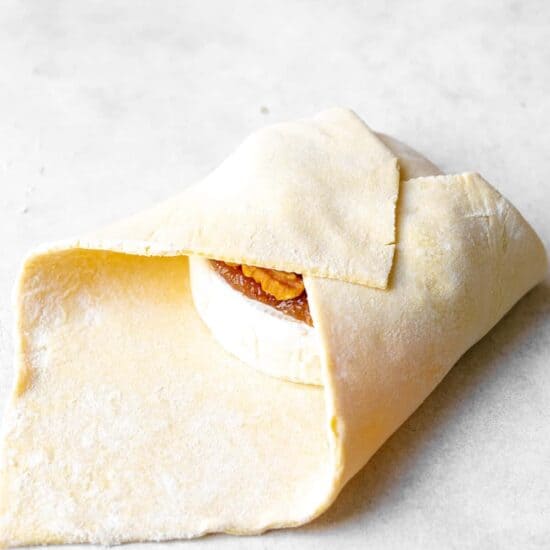 folding puff pastry over brie cheese.