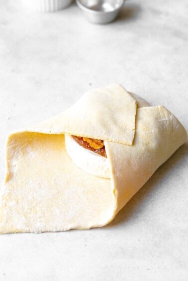 folding puff pastry over brie cheese.