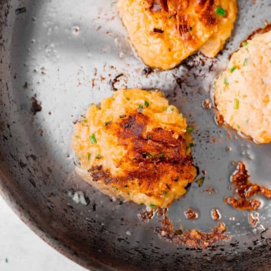 fried leftover cheesy potato pancakes in a frying pan.