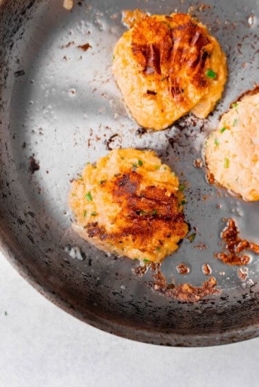 fried leftover cheesy potato pancakes in a frying pan.