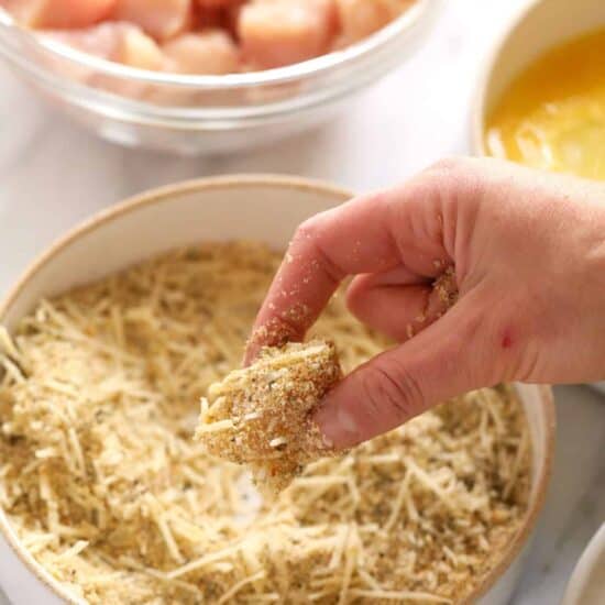 Dipping chicken into bread crumbs.