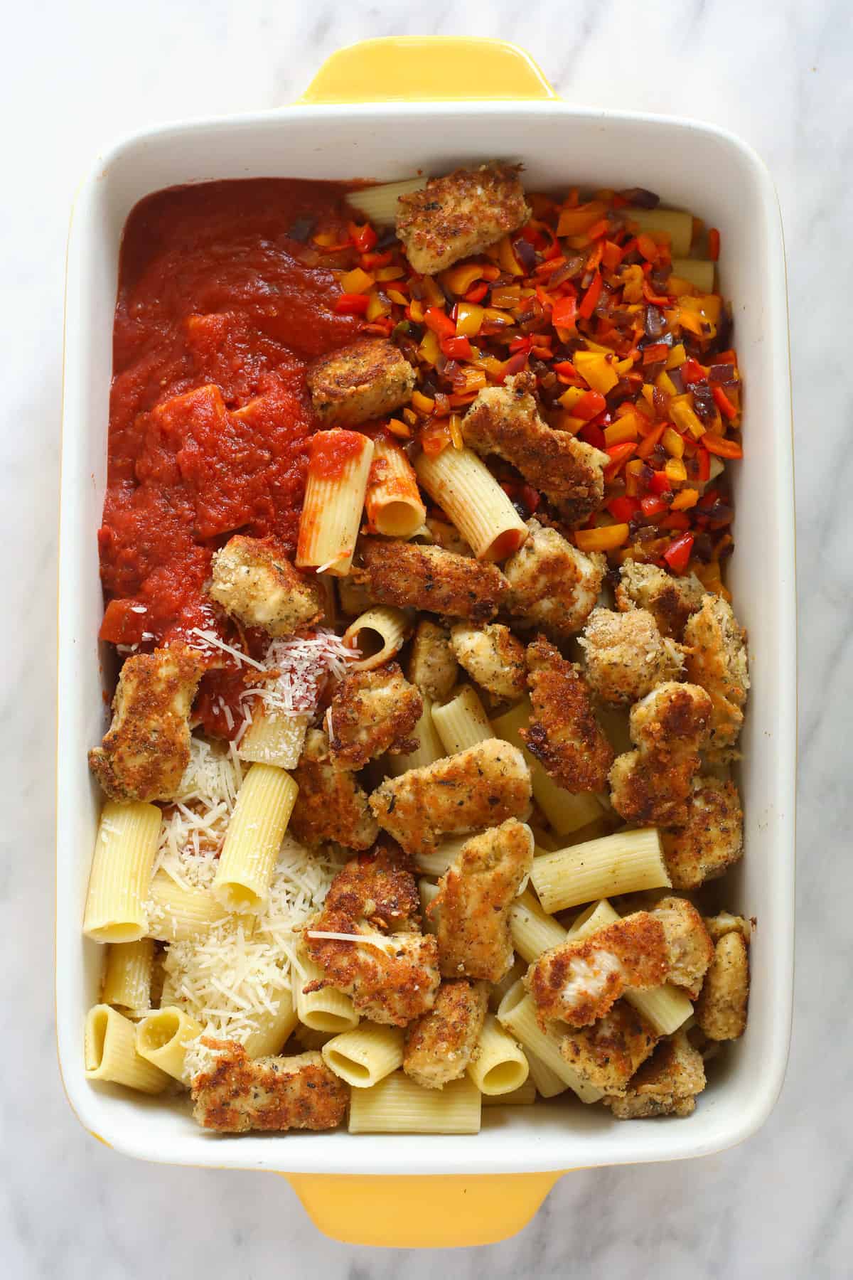 All the ingredients for the chicken parmesan casserole in a casserole dish. 