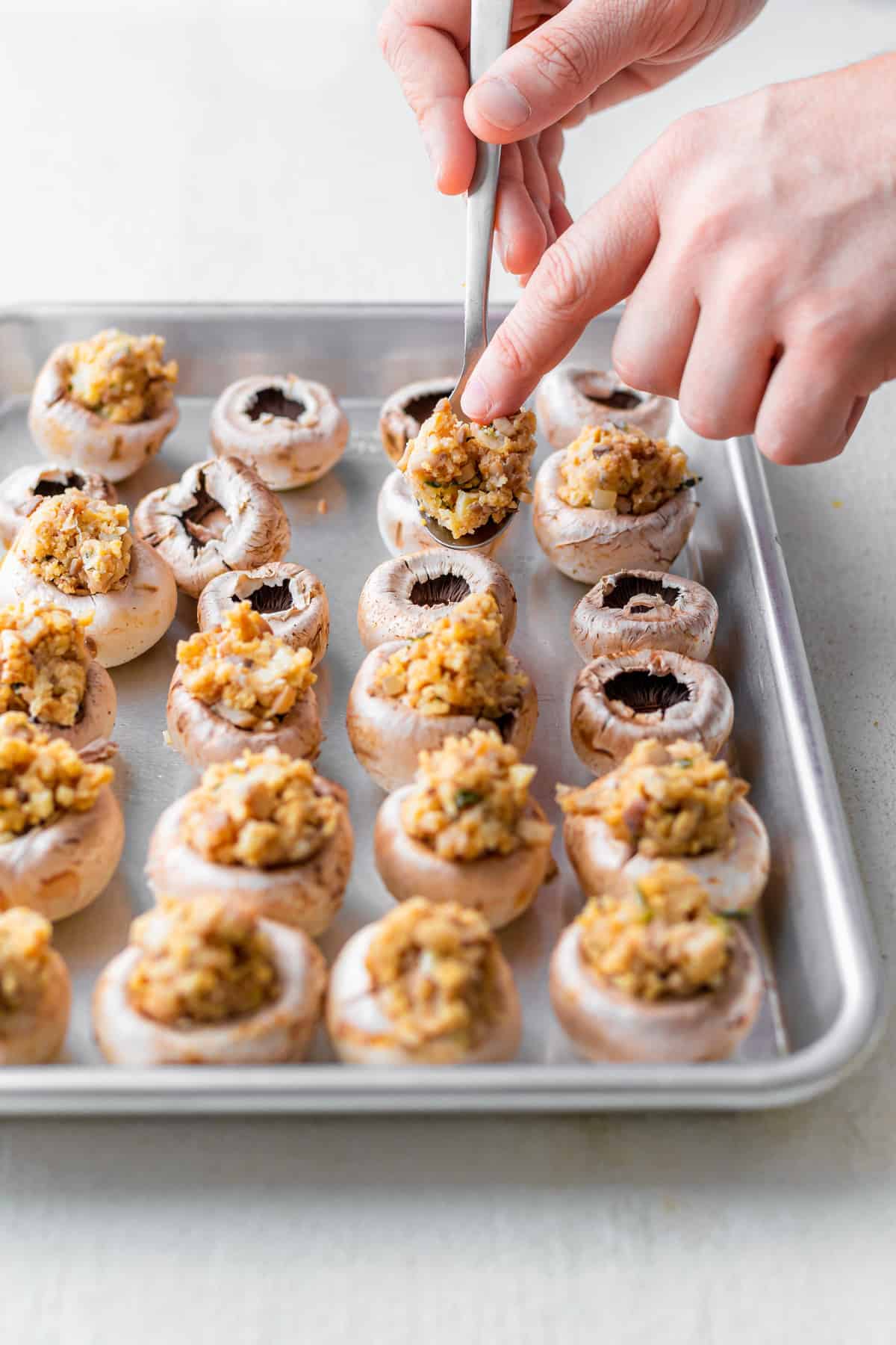 mushroom caps being filled with cream cheese filling for cream cheese stuffed mushrooms