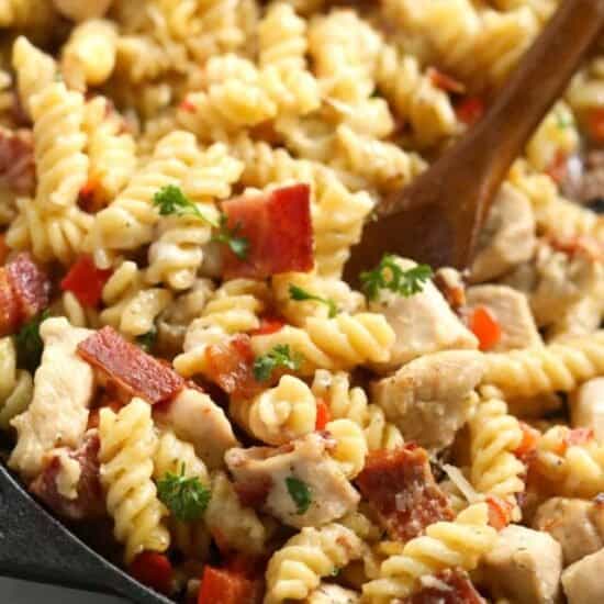 chicken bacon ranch casserole in a cast iron skillet with a wooden spoon