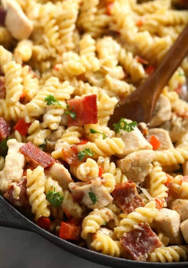 chicken bacon ranch casserole in a cast iron skillet with a wooden spoon