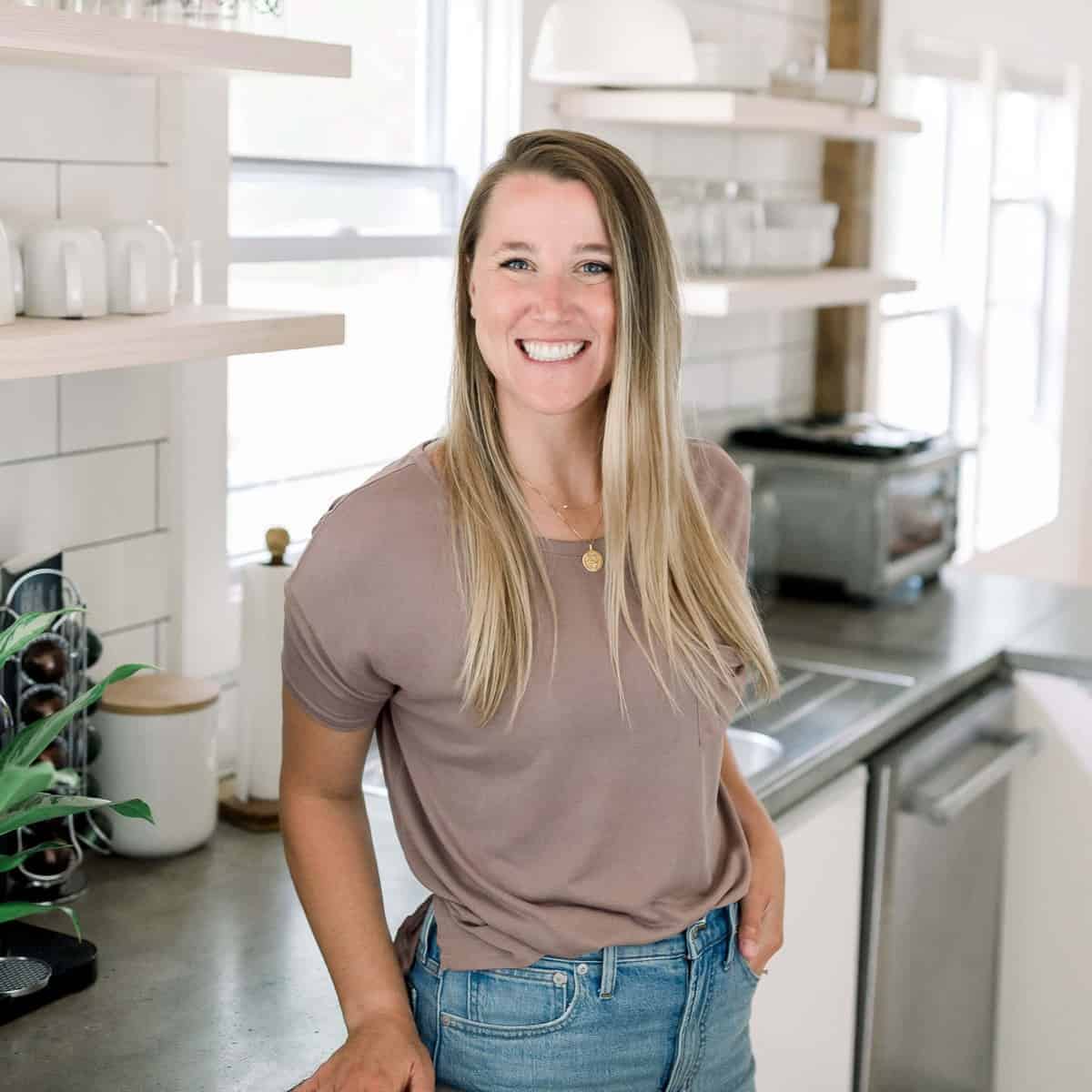 a woman in jeans and a t-shirt standing in a kitchen featuring captivating cheese.