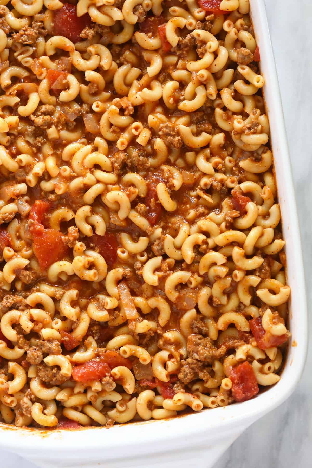 Noodles and tomato sauce in casserole dish.