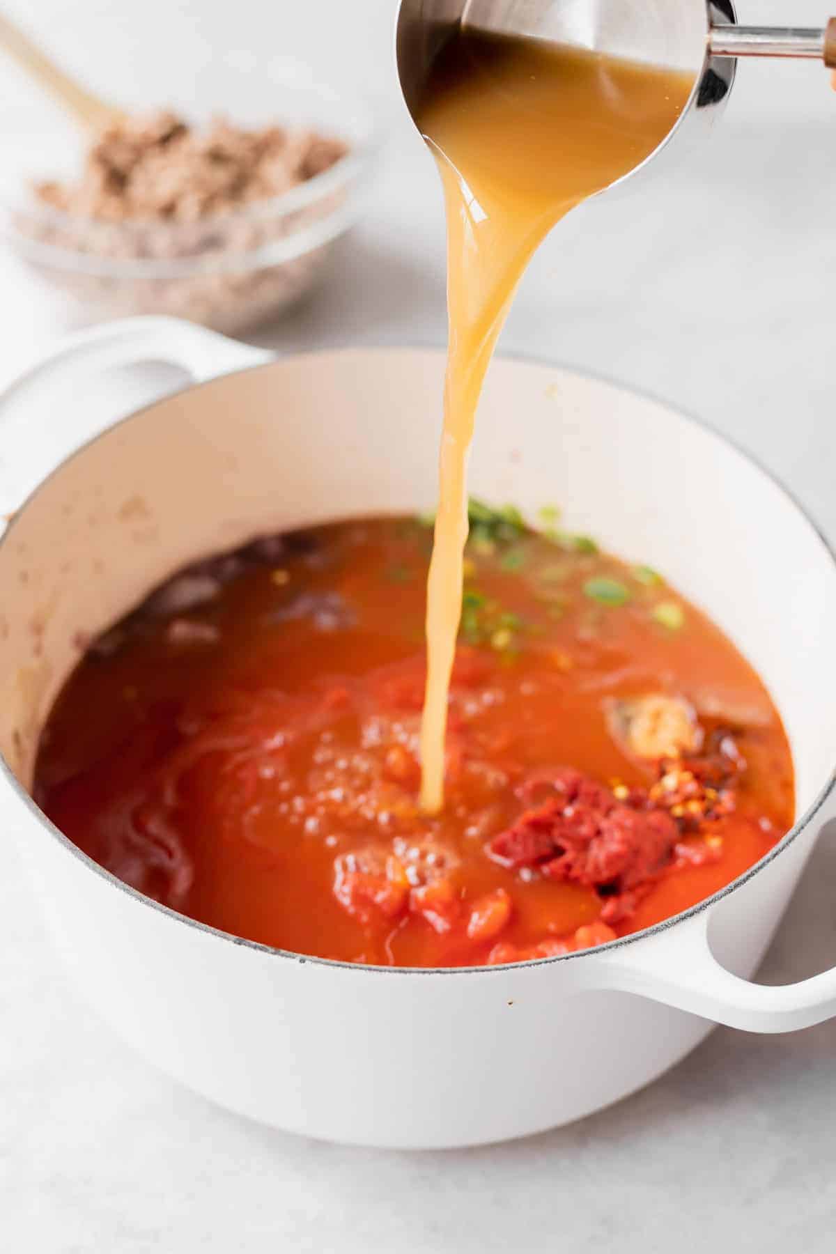 Pouring broth into a dutch oven. 