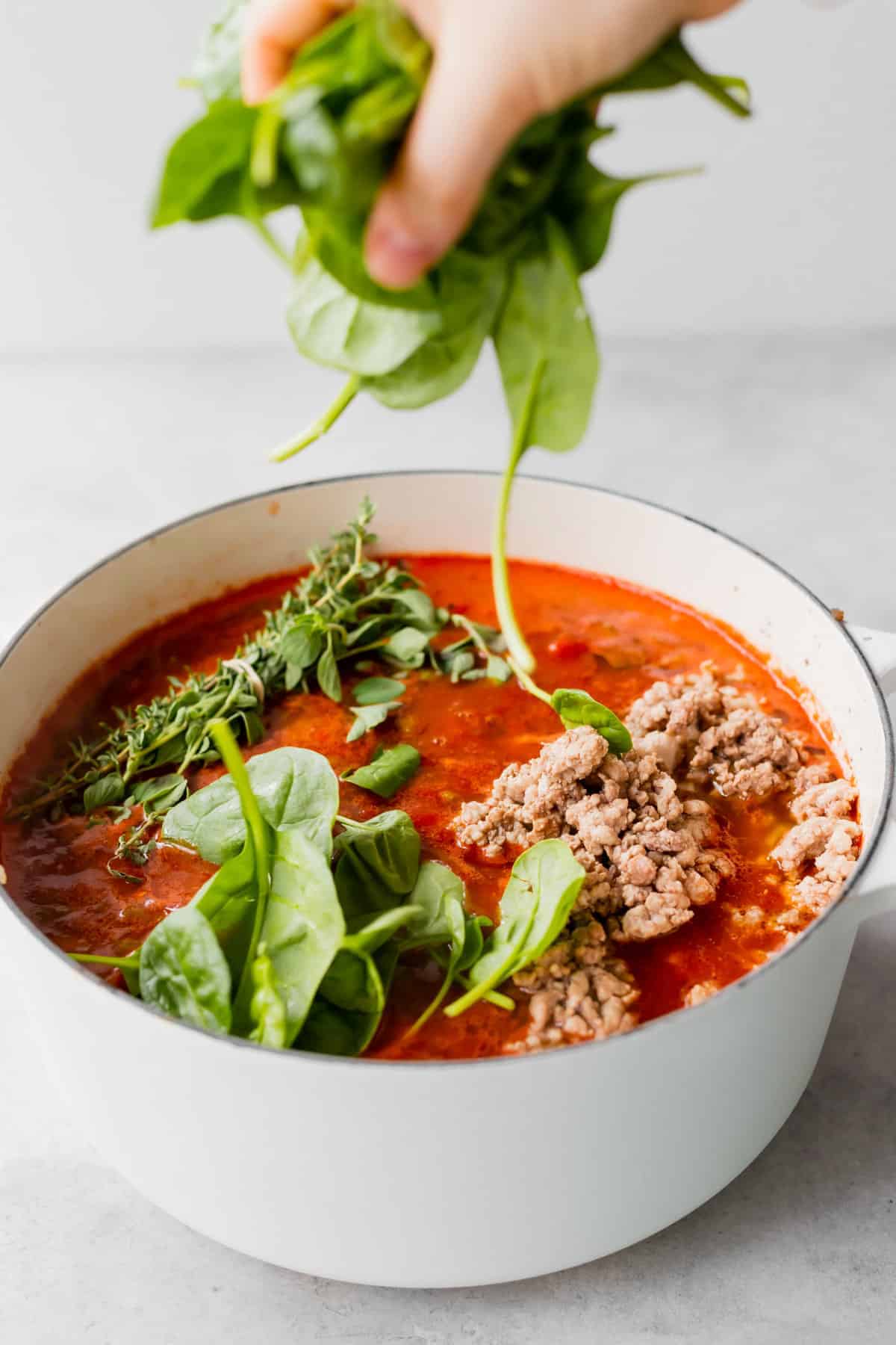 Throwing spinach into lasagna soup. 