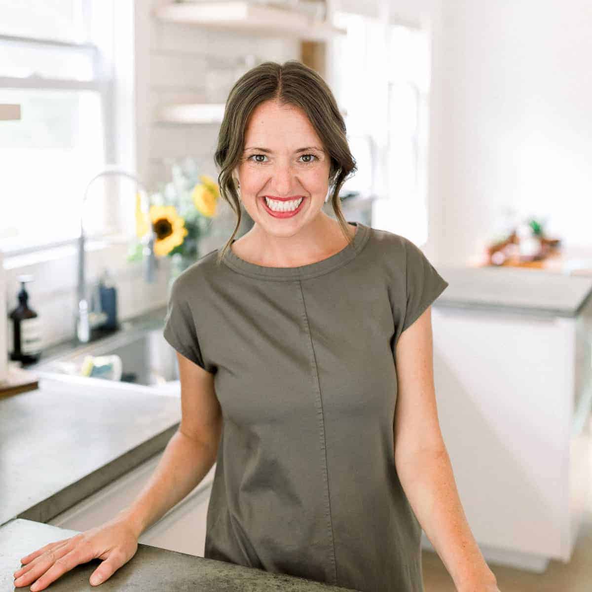 a woman smiling in front of a kitchen counter.