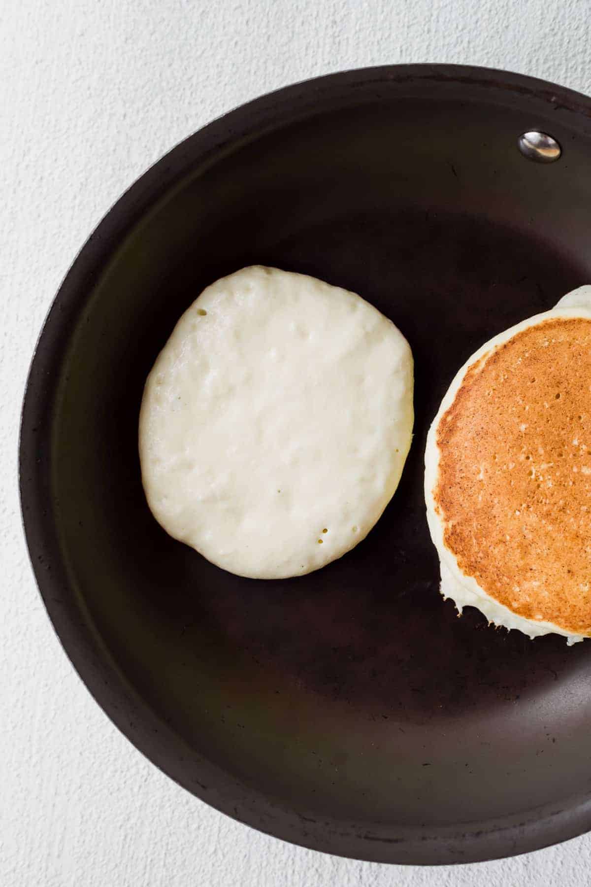 Ricotta pancakes in a skillet looking perfectly golden brown.