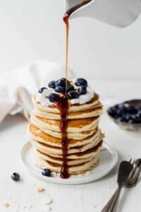 topping pancakes with syrup.