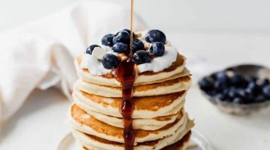 a stack of pancakes with blueberries and syrup.