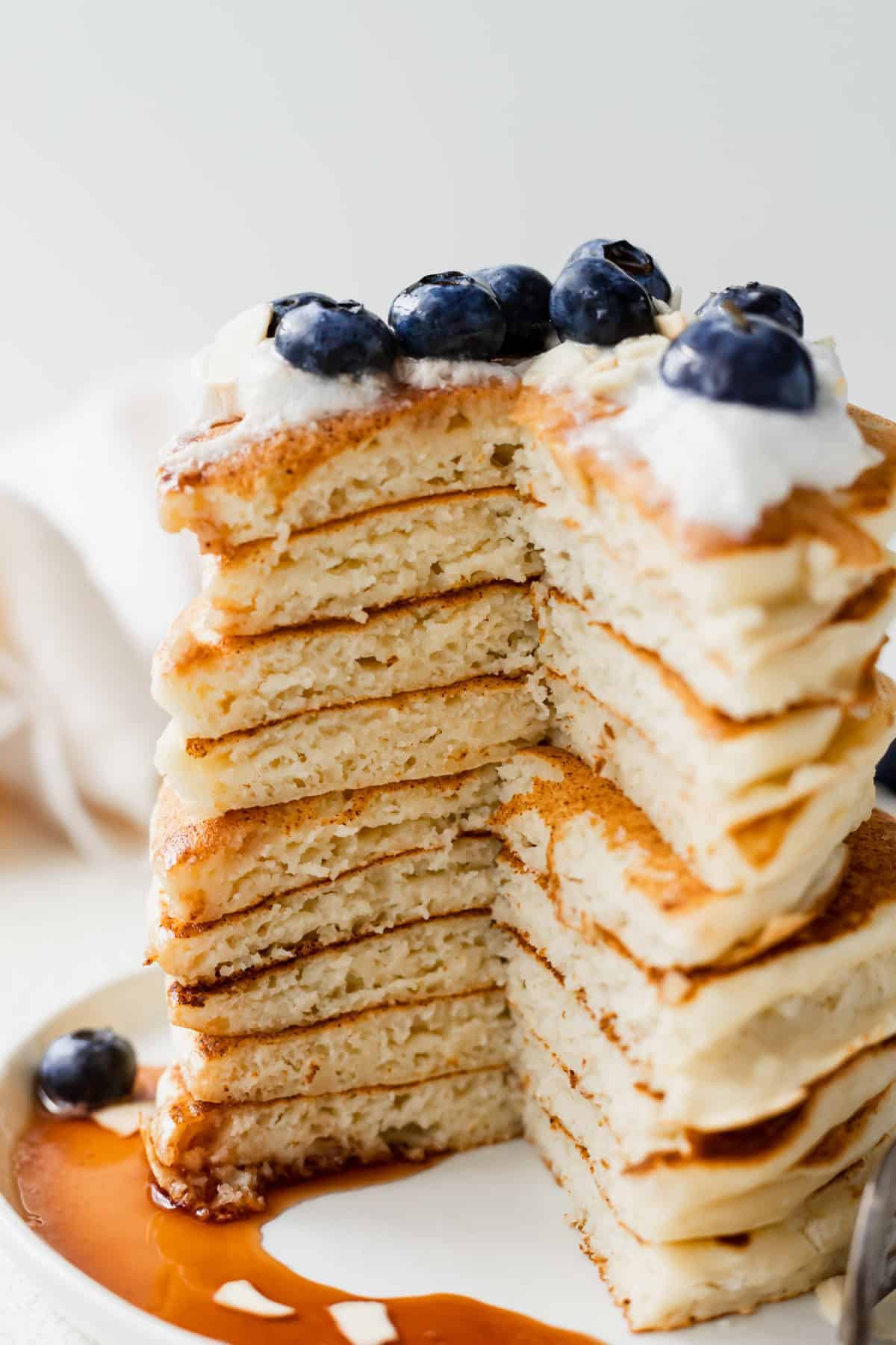 Stack of ricotta pancakes with a slice taken out of it.