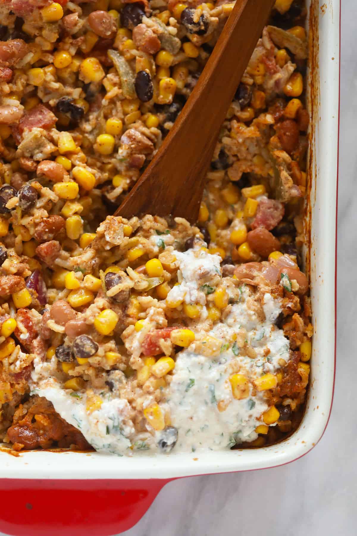 mexican street corn casserole being scooped with a wooden spoon.