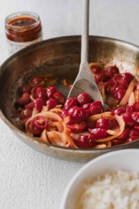 A pan-fried dish showcasing rice and a flavorful cherry sauce, perfect with sun-dried tomato pasta.