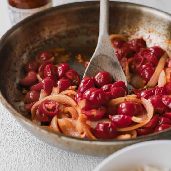 A pan-fried dish showcasing rice and a flavorful cherry sauce, perfect with sun-dried tomato pasta.