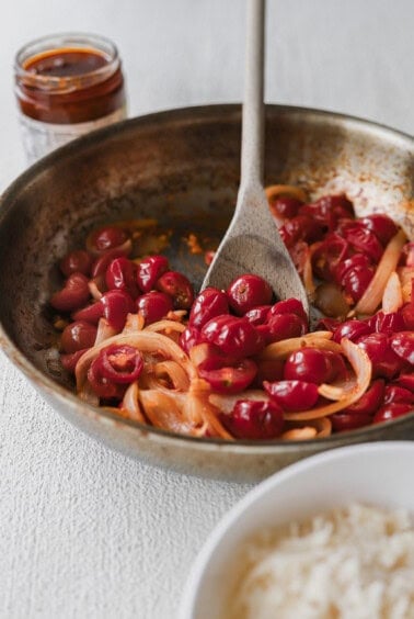 A pan-fried dish showcasing rice and a flavorful cherry sauce, perfect with sun-dried tomato pasta.