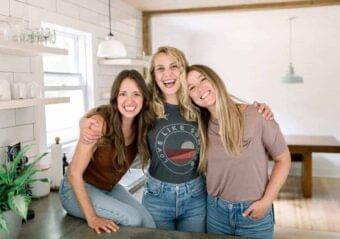 Three women are posing for a photo in a kitchen, showcasing their love for cheese.