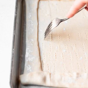 a person using a fork to cut into a tomato tart.