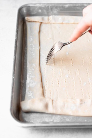 a person using a fork to cut into a tomato tart.