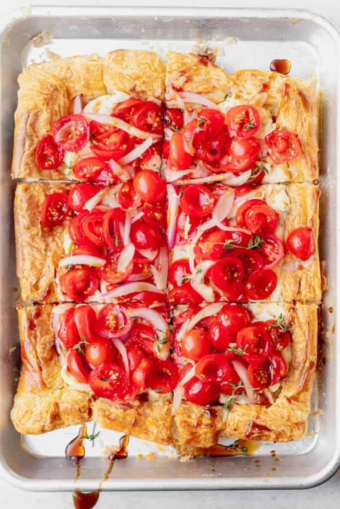 tomato tart on a baking sheet sliced into squares.