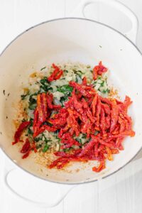 Sauteeing ingredients together for Tuscan Chicken Mac and Cheese.